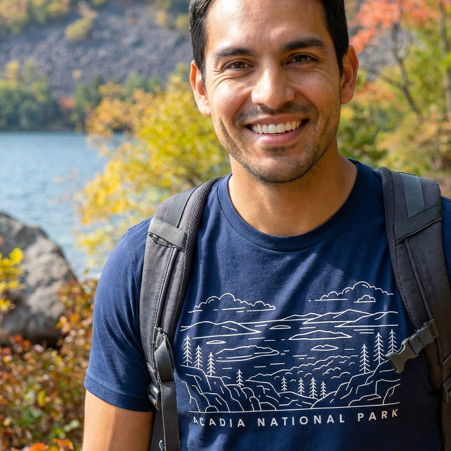 Man hiking a trail wearing a navy Acadia National Park Line Art Tshirt.