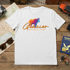 The Glacier – Mountain Goat Script T-Shirt is a white tee with a vibrant mountain goat graphic and "Glacier National Park" in orange text—an ideal Montana souvenir for travel and adventure enthusiasts.