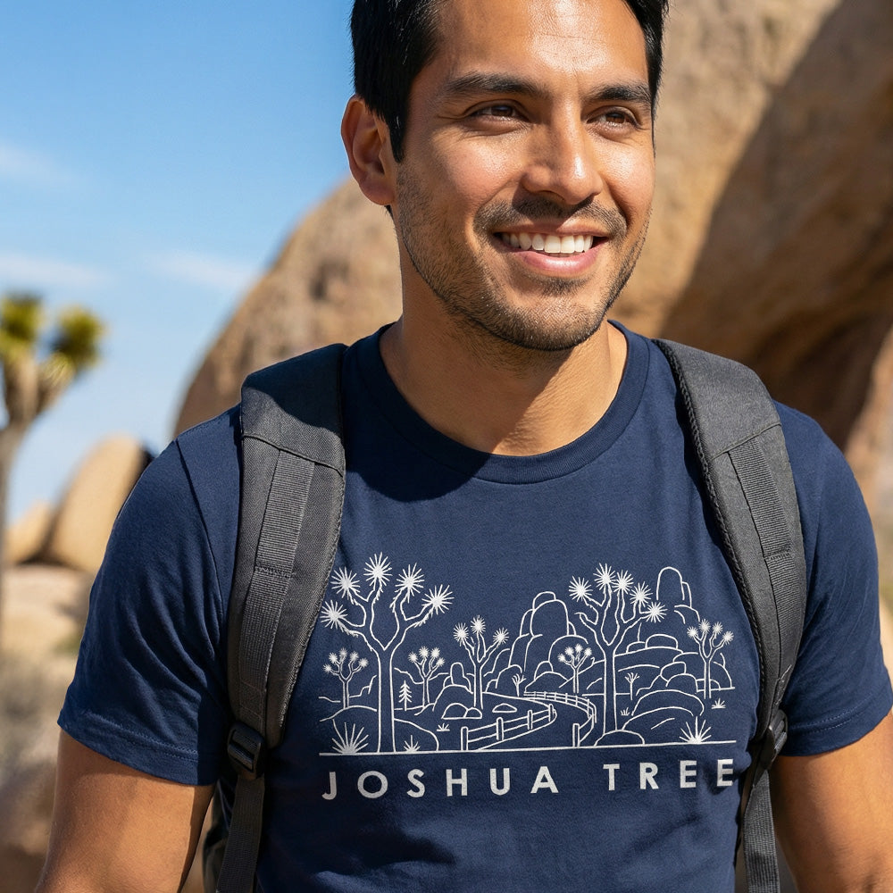 Man hiking a trail wearing a navy Joshua Tree National Park Line Art Tshirt.