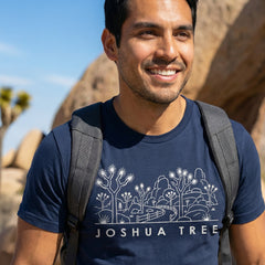 Man hiking a trail wearing a navy Joshua Tree National Park Line Art Tshirt.