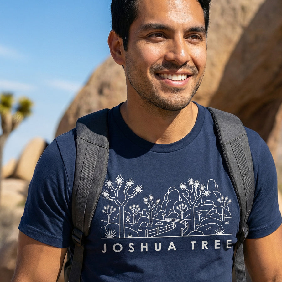 Man hiking a trail wearing a navy Joshua Tree National Park Line Art Tshirt.