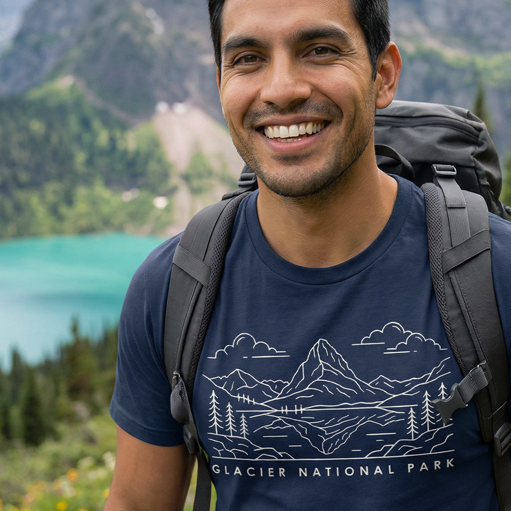 Man hiking a trail wearing a navy Glacier National Park Line Art Tshirt.