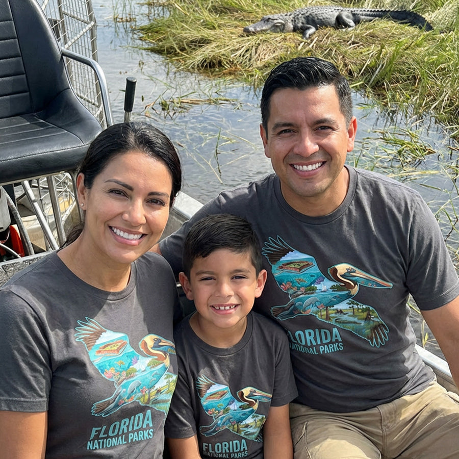 Family of three wearing Florida National Parks Pelican Charcoal T-shirts on a boat in the Everglades